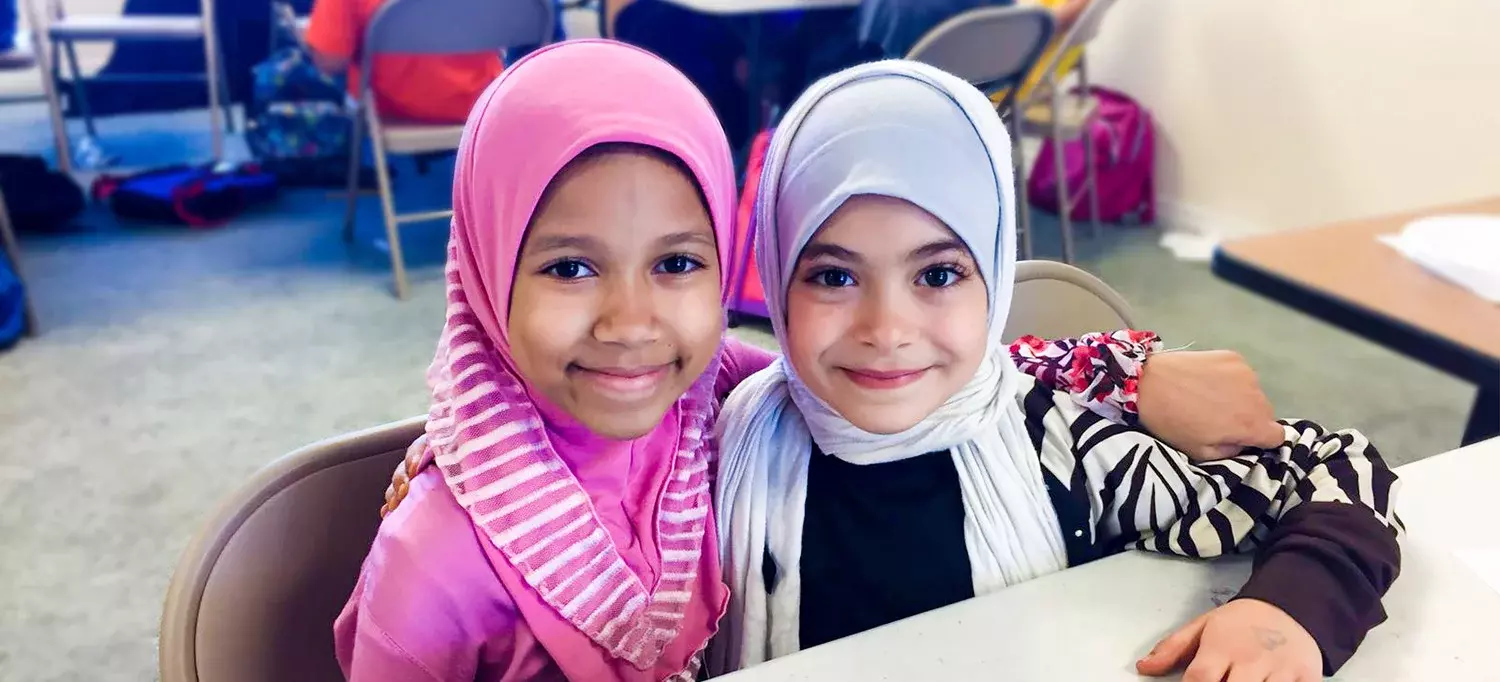 Two smiling young girls at the Islamic School